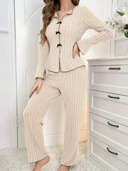 woman standing in cream ribbed knit pajama set with black trim and bows