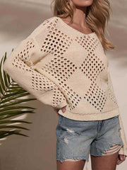 Woman in a cream-colored open-knit sweater with a diamond pattern, paired with distressed denim shorts.