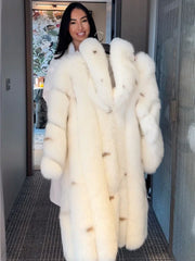 Woman holding a long white faux fur coat on a hanger, smiling.