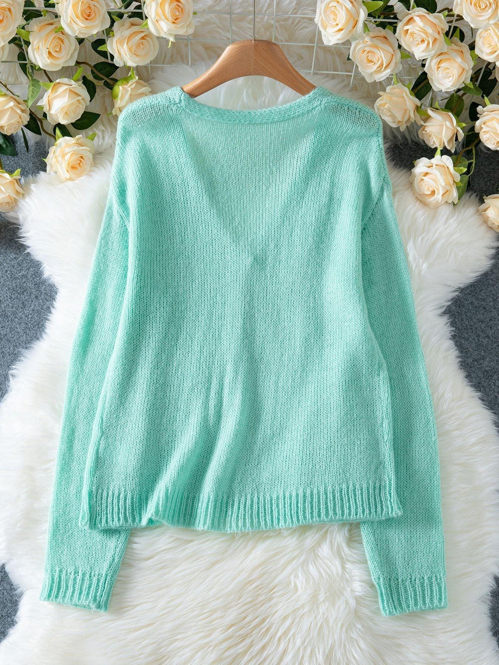 Back view of a light mint green mohair blend cardigan with a V-neck and ribbed hem.