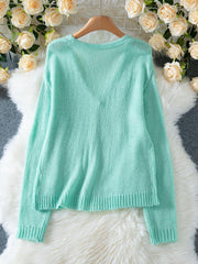 Back view of a light mint green mohair blend cardigan with a V-neck and ribbed hem.