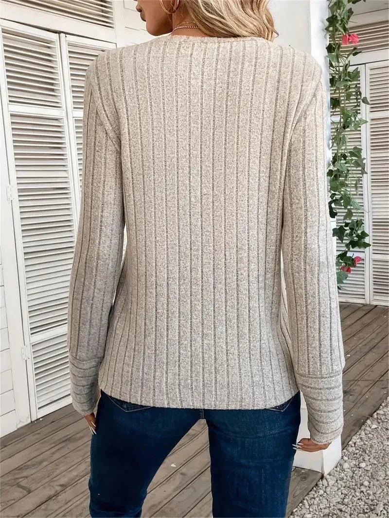 Back view of a woman wearing a cream ribbed long-sleeve crew neck top with dark wash jeans
