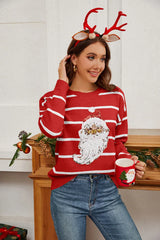 Woman wearing a red striped Christmas sweater with a sequin Santa Claus graphic, holding a Santa mug.