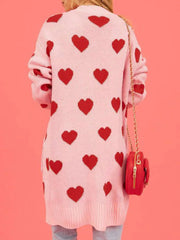 Back view of a woman wearing a pink longline cardigan with a repeating red heart pattern.