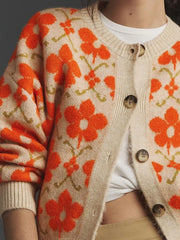Detail of the button closure on the cream knit cardigan with an orange floral print.