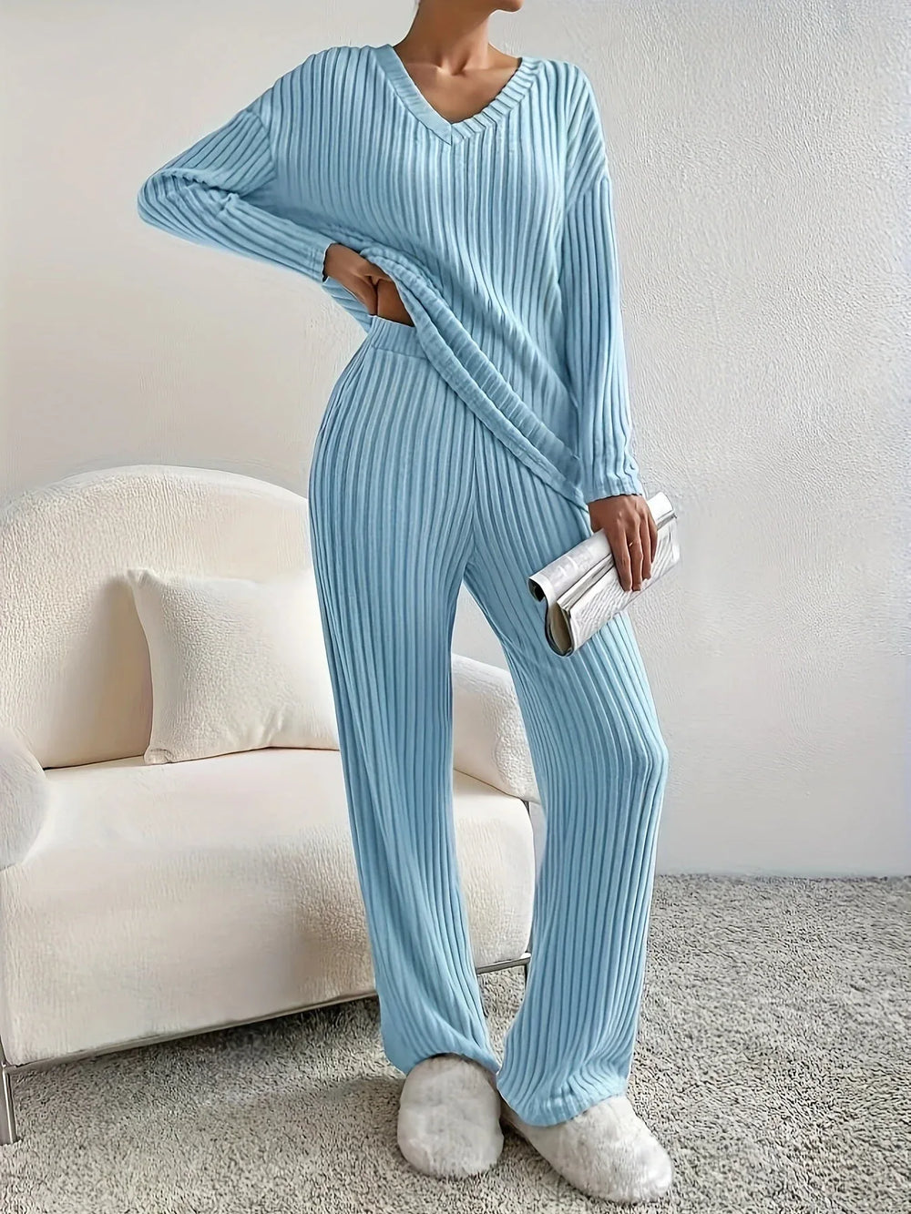 Woman standing with hand on hip in a light blue ribbed loungewear set holding a clutch