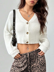 Woman wearing a white cropped knit cardigan, leopard print pants, and a heart pendant necklace, with a black crossbody bag.