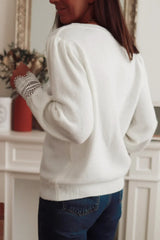 Back view of a woman wearing a white knit sweater with lace trim and blue jeans.