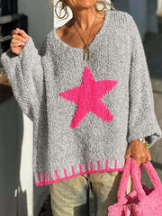 Woman holding a pink bag while wearing a grey knitted sweater with a pink star graphic
