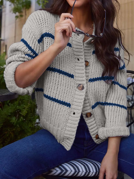 Woman wearing a gray and blue striped knit cardigan with jeans.