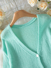 Close-up of the V-neckline and button detail on a light mint green mohair blend cardigan.