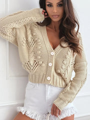Close-up of a cream-colored, open-knit, cropped cardigan with a V-neck and button-up front.