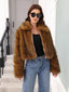Woman in a brown faux fur cropped jacket, black top, and blue jeans, looking at the camera.