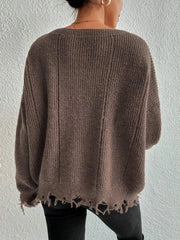 Back view of a woman wearing a brown oversized distressed knit sweater with black pants