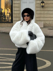 woman wearing a white faux fur cropped jacket with black pants and a black hat