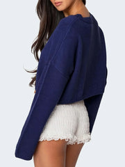 Back view of a navy cropped sweater with a white bow graphic print, worn by a woman.