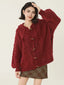 Woman wearing a burgundy cable knit hooded cardigan with toggle button closure and puff sleeves.