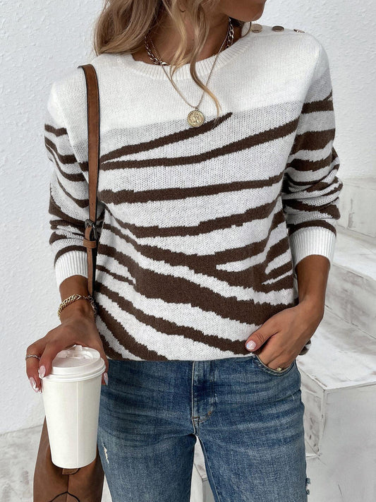 Woman wearing a white and brown striped zebra print knit sweater with blue jeans, holding a coffee cup.
