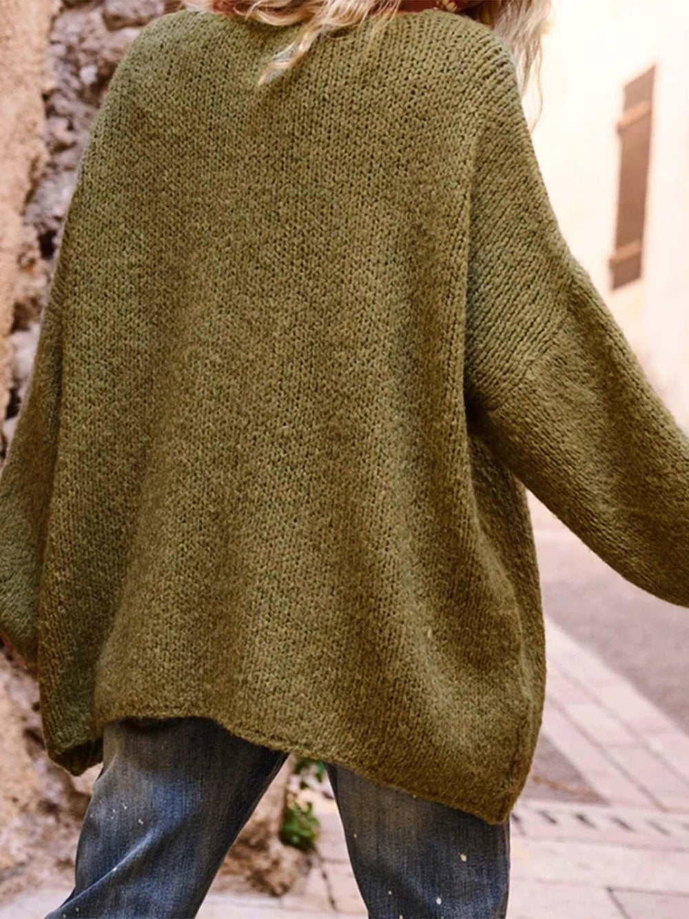 Back view of the green oversized knit sweater, showing the textured knit and relaxed fit.