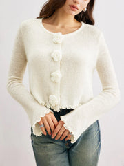 Close-up of the 3D flower buttons on a white knit cardigan.