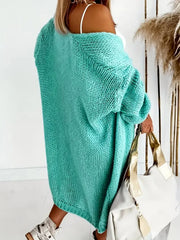 Rear view of a woman wearing a longline aqua knit cardigan, with the cardigan draped off one shoulder.