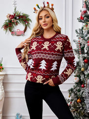 Woman in a festive red sweater with holiday motifs, posing with her hand on her hip.