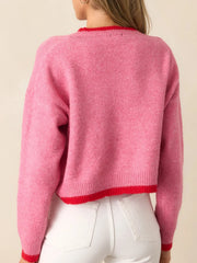Back view of a pink cropped sweater with red trim.
