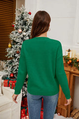Back view of a woman wearing a green long-sleeved crew neck sweater with a sequined candy cane graphic and bow, with a Christmas tree in the background.