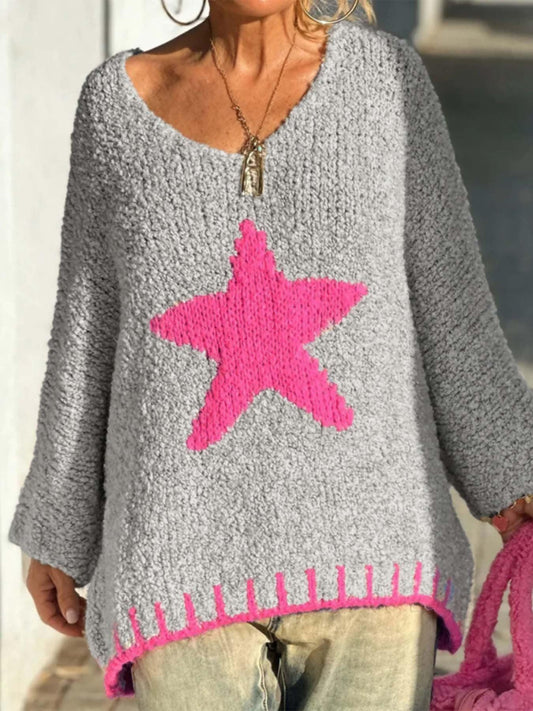 Woman wearing a grey knitted sweater with a large pink star graphic and pink trim