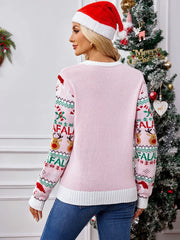 Full body shot of a woman modeling a pink holiday sweater with a playful Christmas print, paired with blue jeans
