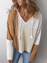 Woman wearing a color block knit sweater with a v-neck and drawstring hood.