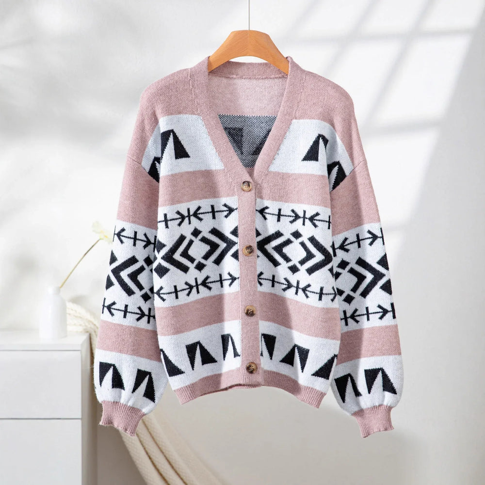 pink and black geometric print knit cardigan hanging on a wooden hanger