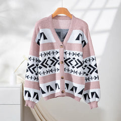 pink and black geometric print knit cardigan hanging on a wooden hanger