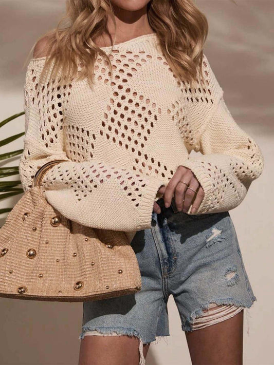 Woman wearing a cream-colored open-knit sweater with a diamond pattern, paired with distressed denim shorts and a straw handbag.
