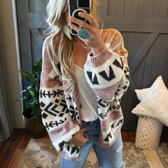 woman wearing a pink and black geometric print knit cardigan with a white tank top and blue jeans