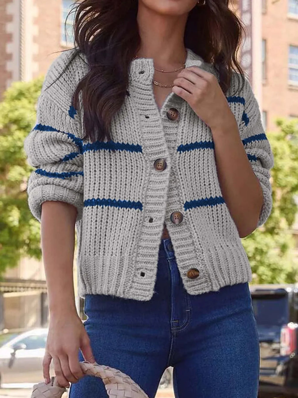 Front view of a woman in a gray and blue striped knit button-up cardigan.