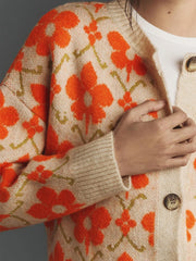 Close-up of the orange floral print on the cream knit cardigan.