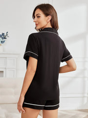 Woman from behind wearing a black short-sleeve pajama top with white piping.