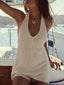 Woman wearing a cream knit halter dress with a deep V-neckline and a gold necklace, standing on a boat with the ocean in the background.