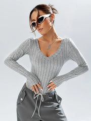 Woman wearing a grey ribbed long-sleeve bodysuit and grey cargo pants, accessorized with white sunglasses and a silver necklace.
