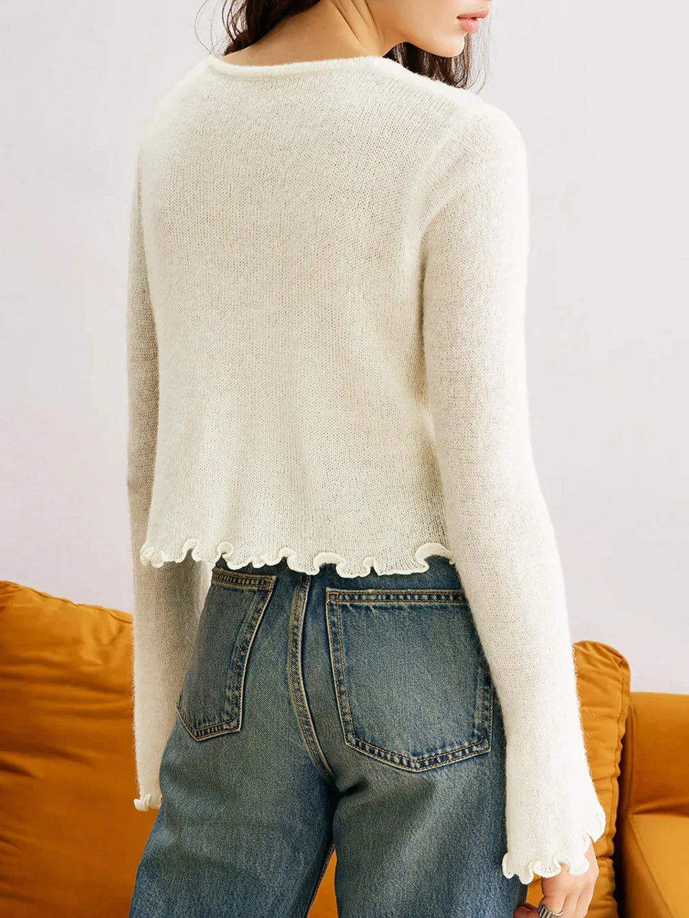Detail of the ruffled hem on a white cropped cardigan.
