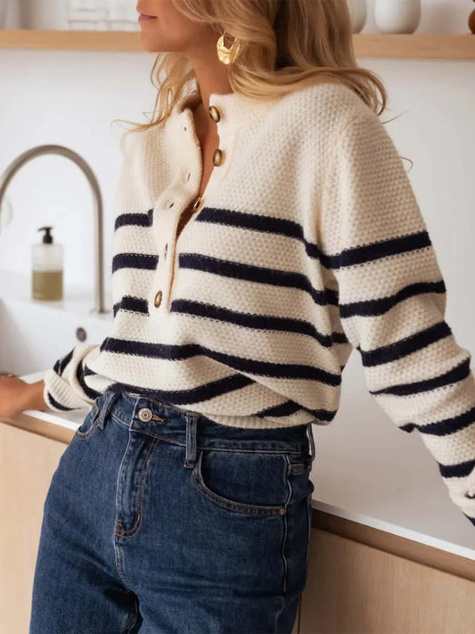 Woman wearing a striped knit sweater and blue jeans, leaning on a counter