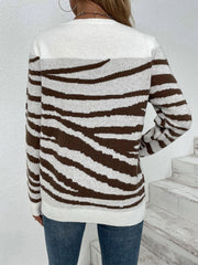 Back view of a woman wearing a white and brown striped zebra print knit sweater with blue jeans.