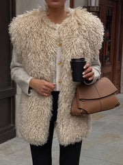 Close-up of a woman wearing a beige shaggy faux fur vest over a grey cardigan with gold buttons, holding a black coffee cup and a brown leather handbag.