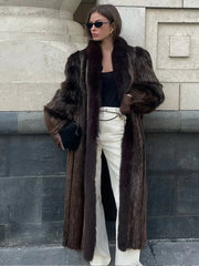 woman wearing a long brown fur coat with white pants and black accessories