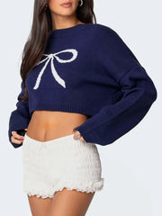 Front view of a navy cropped sweater with a white bow graphic print, worn by a woman.