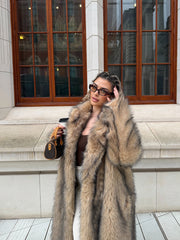 Fashionable woman in a statement faux fur coat, styled with sunglasses and a small handbag.