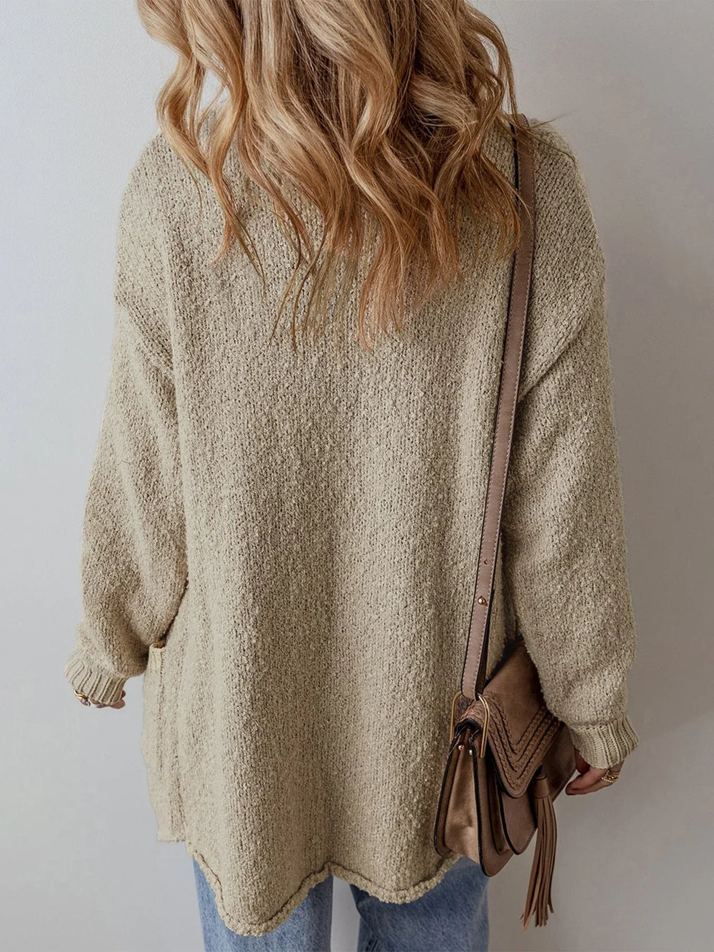 Back view of a woman wearing a long beige knit cardigan