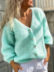 Woman wearing a light mint green mohair blend cardigan with a V-neck and button-down closure.
