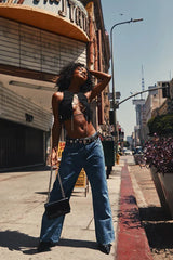 Woman posing in a black cropped top with a lace-up rhinestone front and jeans outdoors